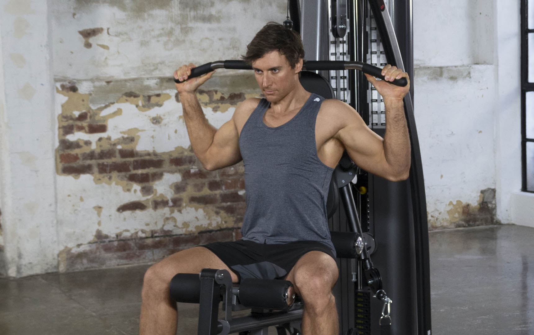 man in gray tank top working out on a weider home gym