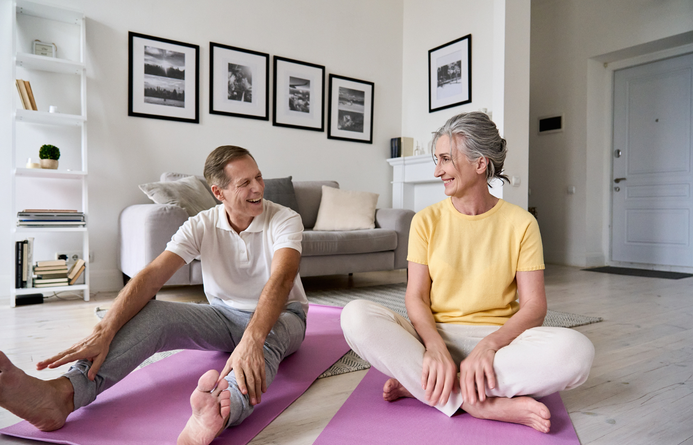 An elderly couple sitting on yoga mats before a workout
