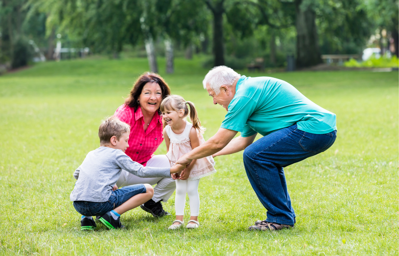 Grandparents playing outside on the grass with their grand children