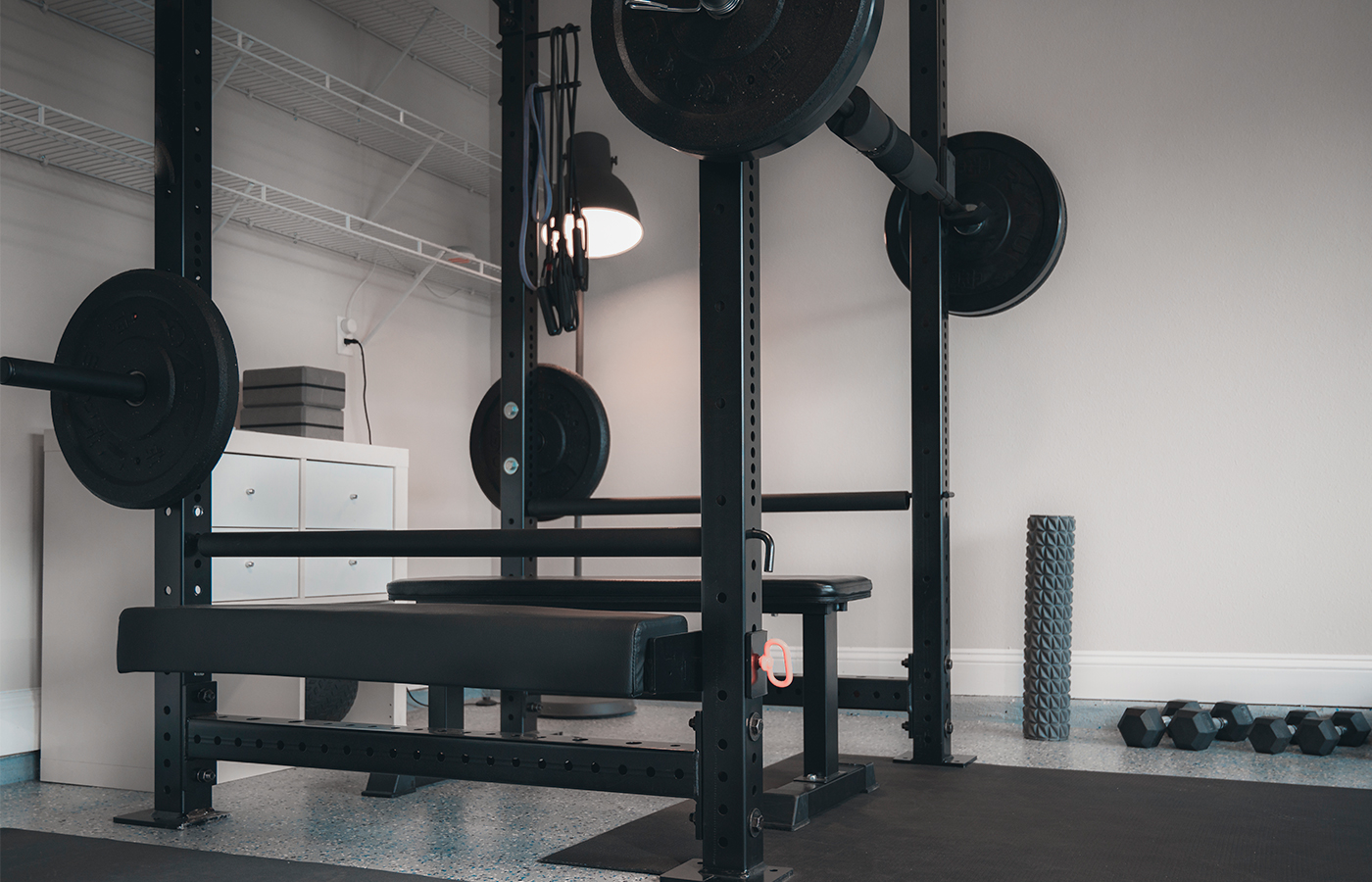 A home gym in the garage with a bench and weights